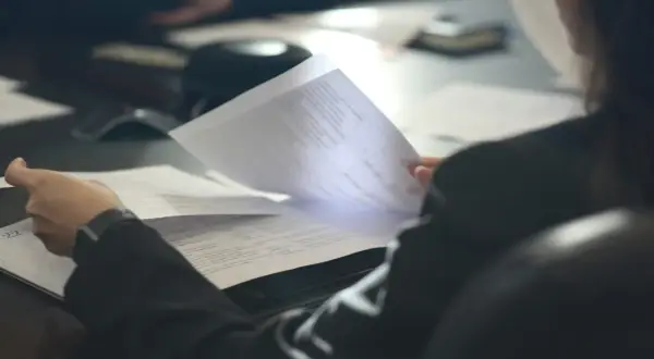 Osoba przegląda dokumenty, analizując pozaszkolne formy edukacji PKD.