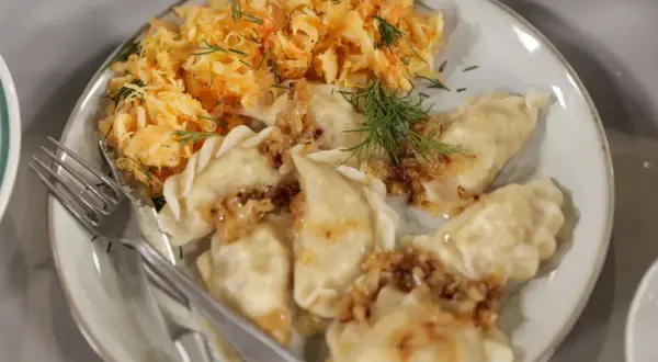 Pyszne pierogi z cebulką i koperkiem, podane z surówką z kiszonej kapusty. Idealne na mandu menu.