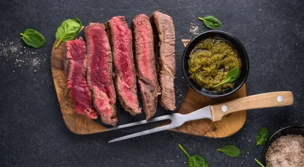 Perfekt gegrilltes Steak, in Scheiben geschnitten, mit Kräutersauce und frischem Spinat. Ein Genuss für jeden Fleischliebhaber.