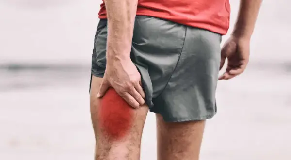 Un corridore si tiene la coscia, evidenziata in rosso, a causa di gambe intorpidite.
