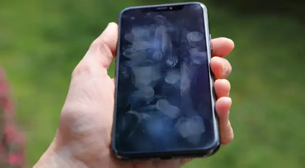 Dłoń trzyma smartfon z licznymi śladami palców na ekranie. Czy to efekt braku szkła hartowanego 9D?