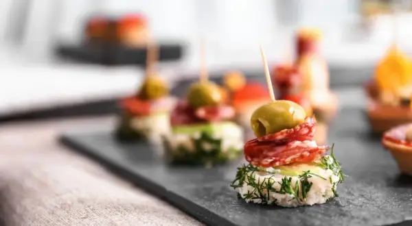 Wykwintne koreczki na imprezę: oliwka, salami i świeży koperek na chrupiącym pieczywie. Idealne na przyjęcie!