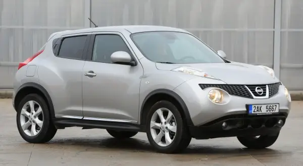 Srebrny Nissan Juke, często chwalony w nissan juke opinie, prezentuje się dynamicznie na tle nowoczesnej architektury.