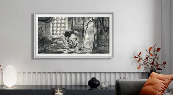 Mickey Mouse blickt in einen Spiegel. Ein moderner Fernseher, der wie ein Bild aussieht, hilft, Technik im Wohnzimmer zu verstecken.