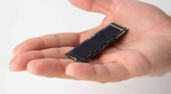 Dłoń trzyma mały dysk SSD M.2. Jego czarna powierzchnia lśni, gotowa do optymalizacji dzięki funkcji ssd trim.