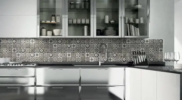 Cucina moderna con ante lucide in acciaio cromato o inox, piastrelle decorate e pensili in vetro.
