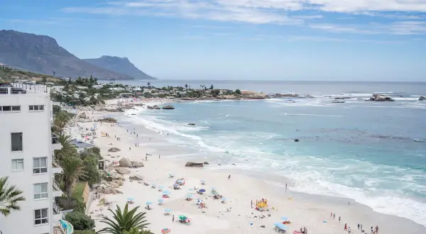 Sonniger Strand in Kapstadt mit vielen Menschen, die entspannen. Die Frage "ist Kapstadt sicher?" scheint hier positiv beantwortet.
