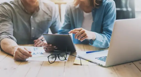 Para uchronić się przed oszustwami związanymi z kredytem na PESEL, para analizuje dane na tablecie i laptopie.