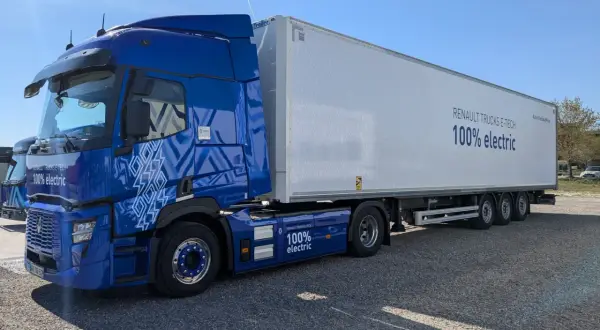 Un camion renault electrique bleu vif, avec une remorque blanche arborant le message "100% electric".