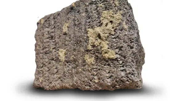En bit porös, mörkgrå sten med ljusare gula partier. Så här ser blåbetong ut, en lätt och isolerande sten.