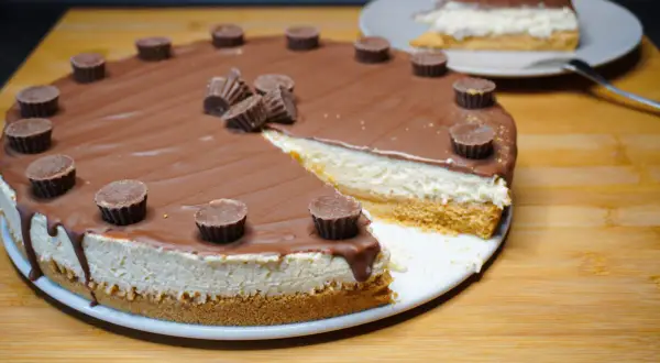 Reese's Torte mit Schokoladenglasur und Erdnussbutter-Cups. Ein Stück ist bereits angeschnitten.