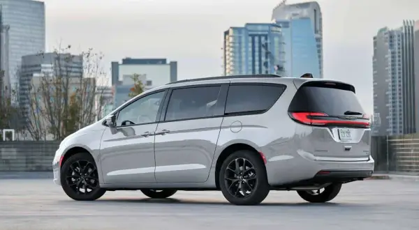 Srebrny Chrysler Pacifica z czarnymi felgami na tle nowoczesnych budynków miejskich.