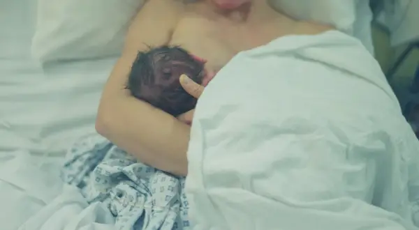 Mama karmi noworodka piersią. To piękny moment w połogu, pełen bliskości i miłości.