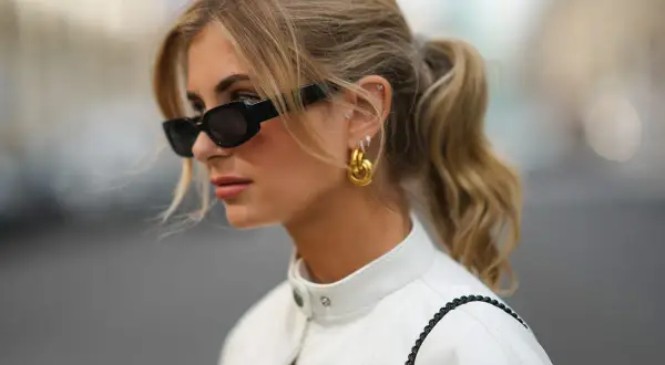 Mujer con coleta y gafas de sol, luciendo un corte de pelo con flequillo cortina que enmarca su rostro.