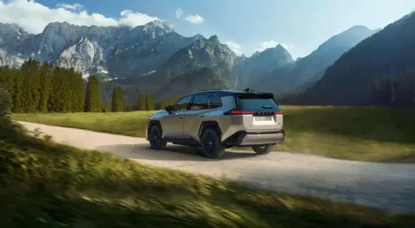 Srebrny Toyota RAV4 pokonuje szutrową drogę w górskim krajobrazie. Idealny do przygód off road.