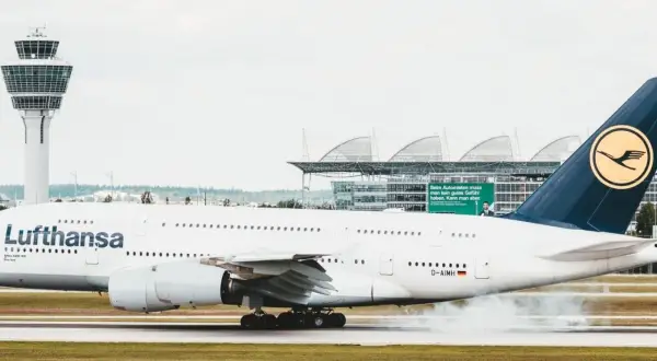 Lufthansa-Flugzeug landet auf dem Rollfeld, Rauch steigt auf.