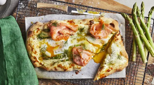 En läcker pizza med rökt lax, ägg och sparris, som en italiensk dröm på en tallrik.