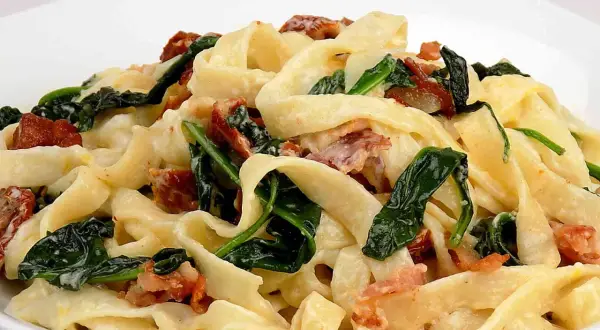 Pyszny makaron tagliatelle z kremowym sosem mascarpone, szpinakiem i chrupiącym boczkiem.