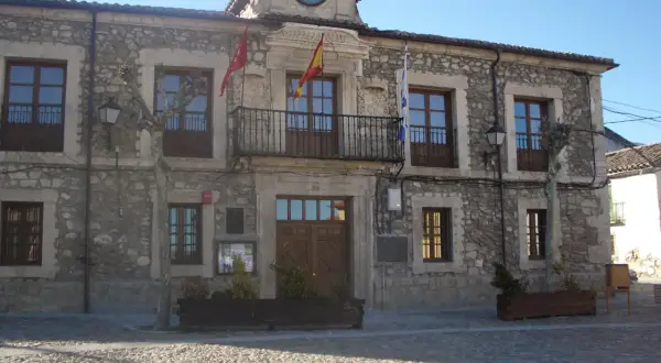 Ayuntamiento de Lozoyuela, con su fachada de piedra, balcón y reloj. Un lugar con mucho que ver.
