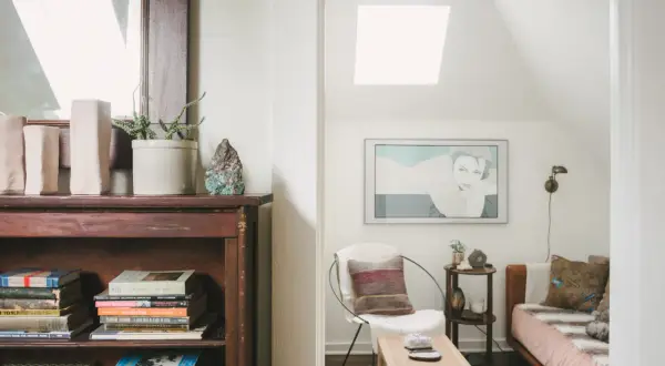 Accogliente libreria in mansarda con un letto, una poltrona e un quadro.