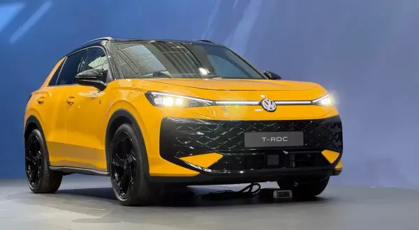 Żółty Volkswagen T-Roc z czarnym dachem i felgami. Zbliżenie na przód auta, gdzie widoczne są światła LED i atrapa chłodnicy. T roc wymiary sugerują kompaktowy SUV.