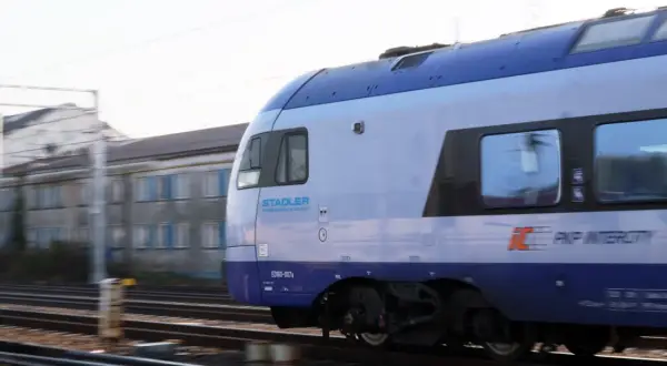 Pociąg PKP Intercity Stadler ED160-007a mija budynek w ruchu. Może to być podróż z Chełma do Krakowa.