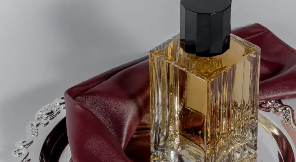Elegancka butelka perfum na ozdobnej tacy, otulona bordową skórą. To wyjaśnia, dlaczego znana modelka nigdy nie używa tradycyjnych perfum z drogerii.