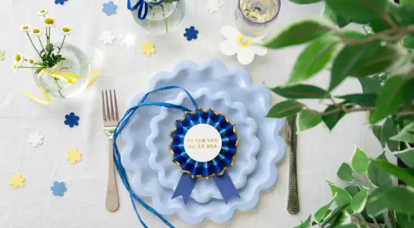 Blå tallrikar med en rosett som säger "Fy fan vad du är bra". Perfekt student dekoration inspiration med blommor och konfetti.