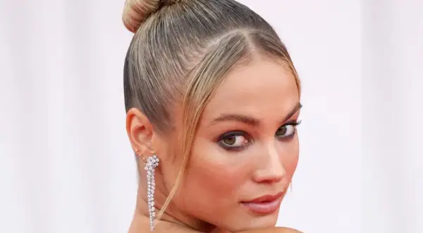 Elegancka, gładka fryzura typu sleek bun z błyszczącymi kolczykami.