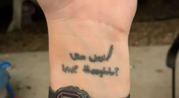 Tatuaz na opalonej skorze z napisem "Who would have thought?".