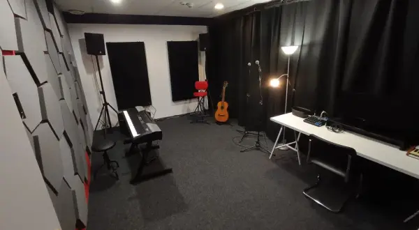 Studio nagraniowe z pianinem, gitarą i mikrofonami. Akustyka pomieszczenia, gdzie może pojawić się jitter, jest poprawiona przez specjalne panele na ścianach.