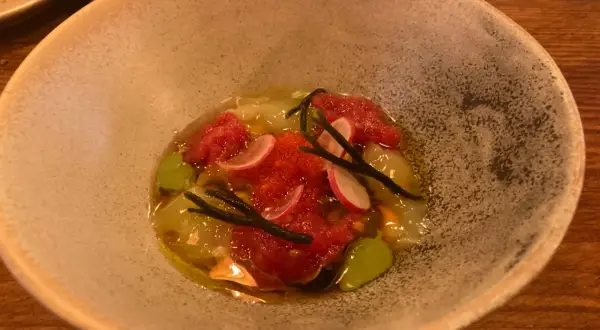 Un plato de mariscos con tomate picado, rábano y algas, servido en una **taberna oeste**.