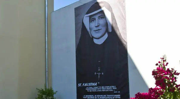 Plakat z portretem św. Faustyny na ścianie budynku, z napisem "ST. FAUSTINA".