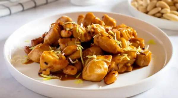 Un invitante piatto di pollo alle mandorle, lucido e saporito, guarnito con erba cipollina.