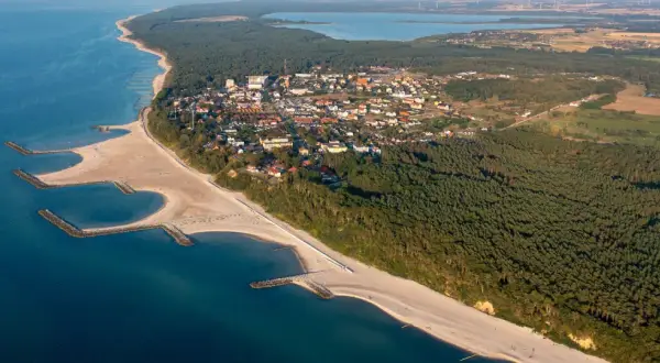 Jarosławiec atrakcje: malownicza plaża z falochronami, las sosnowy i zabudowania kurortu widziane z lotu ptaka.