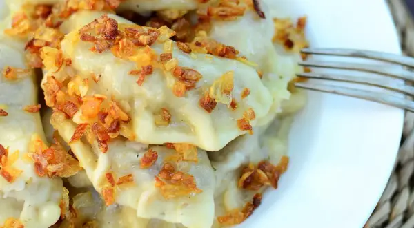 Pyszne pierogi z kaszą gryczaną i twarogiem, posypane chrupiącą cebulką. Idealne na obiad!