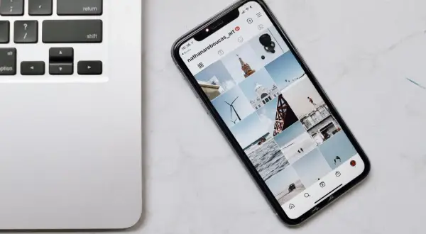 Telefon z Instagramem obok klawiatury laptopa. Dowiedz się, jak połączyć telefon z laptopem, aby łatwo przesyłać zdjęcia.