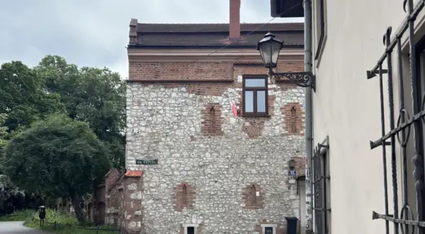 Kamienna ściana z ceglanymi elementami, przypominająca najstarszy dom w Polsce. Ulica Św. Krzyża.