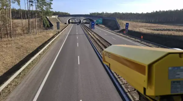 Żółta kamera rejestruje prędkość na drodze. To system odcinkowy pomiar prędkości, który dba o bezpieczeństwo kierowców.