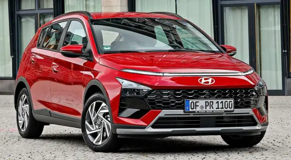 Czerwony Hyundai Bayon z nowoczesnym designem, błyszczącym lakierem i charakterystycznym grillem, zaparkowany na brukowanej ulicy.