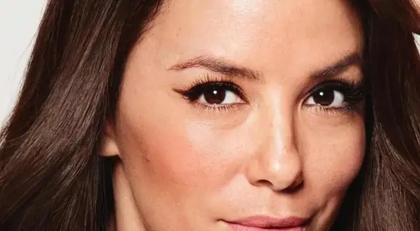 Primer plano de una mujer con pelo fosco y oscuro, ojos marrones con delineado cat eye y piel con rubor.