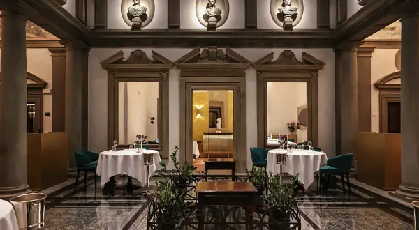Lussuoso ristorante con tavoli apparecchiati, busti antichi e colonne. Un'atmosfera da vero atto di vito mollica.