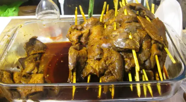 Szaszłyki z wątróbki, przypominające smakiem dania z Peru, zanurzone w ciemnym sosie.