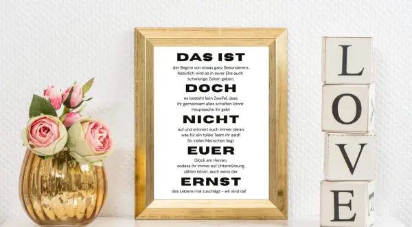 Das Geheimnis einer guten Ehe lustig: Ein gerahmter Spruch über Teamwork und Unterstützung, daneben LOVE-Blöcke und Rosen.