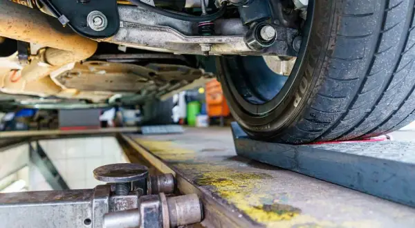 Podczas regulacji zbieżności kół w warsztacie samochodowym, mechanik precyzyjnie ustawia zawieszenie.