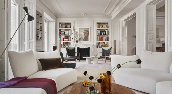 Elegante salón con sofás blancos, chimenea y estanterías, un ejemplo de un estudio de arquitectura e interiorismo.