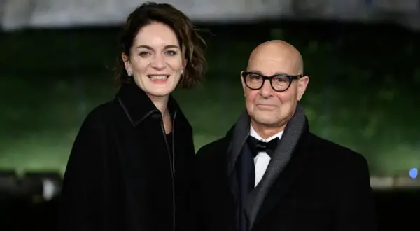 Felicity Blunt y Stanley Tucci sonríen a la cámara, vestidos elegantemente para un evento.