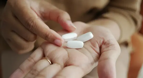 En hand håller tre vita tabletter, kanske för att visa sertralin 25 mg effekt.