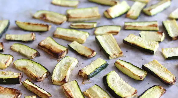 Skivor av zucchini i ugn, lätt gyllene och kryddade, redo att serveras.