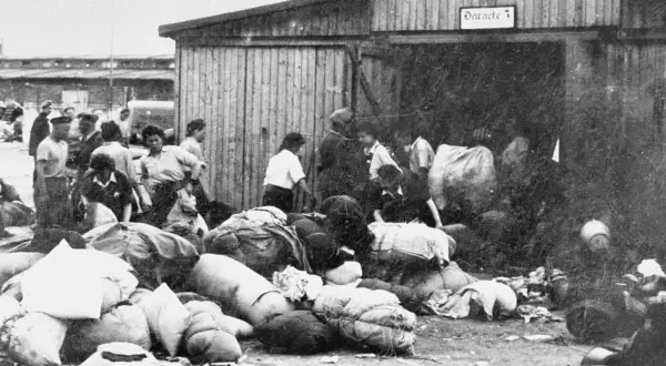 Ludzie z bagażami przed barakiem w Auschwitz. To krótkie streszczenie tego, co działo się w obozie.